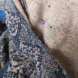 May include: A close-up of a brown fabric with a snake skin pattern. The fabric has several small holes in it.