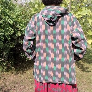 May include: A hooded shirt with a black, green, and pink geometric pattern. The shirt has a long sleeve and is made of a soft, comfortable fabric.