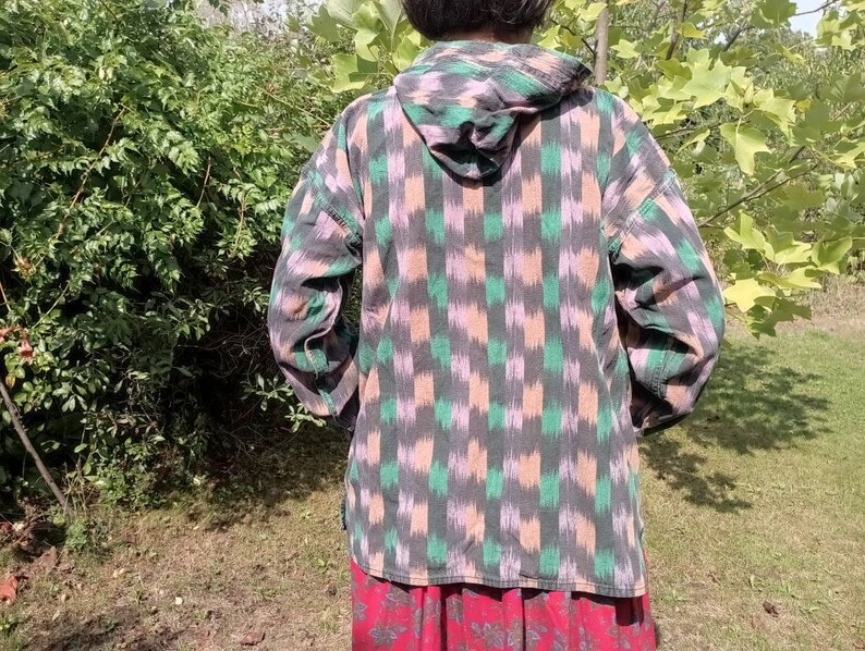 May include: A hooded shirt with a black, green, and pink geometric pattern. The shirt has a long sleeve and is made of a soft, comfortable fabric.