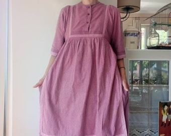 Könnte beinhalten: Ein rosa-weiß gemustertes Kleid mit Knopfleiste und gerafftem Rock. Das Kleid hat einen mehrlagigen Rock mit einer einfarbigen rosa Unterlage.