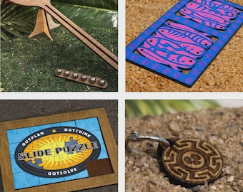Könnte beinhalten: Eine Sammlung von Holzpuzzles und -spielen. Enthält ein Holzpaddel mit einem Kugellagerspiel, ein blaues und rosa dekoratives Holzstück, ein Schiebepuzzle mit dem Text "Slide Puzzle" und einen Holzschlüsselanhänger mit einem Labyrinth-Design.