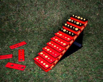 Könnte beinhalten: Eine rote Holztreppe mit gelben Kreisen auf jeder Stufe. Die Treppe steht auf einem schwarzen Ständer und ist von grünem Gras umgeben.