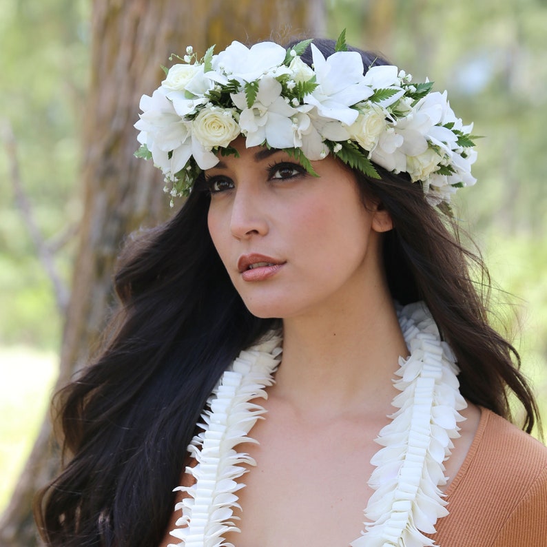 Puede incluir: Una mujer con un collar de flores blancas y una corona de flores blancas. El collar est&aacute; hecho de flores blancas y la corona est&aacute; hecha de flores blancas y hojas verdes.