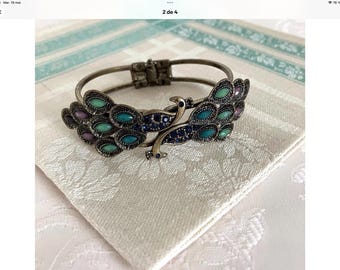 Hinged bangle bracelet in gold-tone metal, peacock design, adorned with blue, green and purple rhinestones