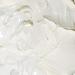 May include: Close-up of a textured, white substance with a glossy sheen. The image shows a thick, creamy material with irregular shapes and a smooth, reflective surface. The overall effect is one of purity and freshness.