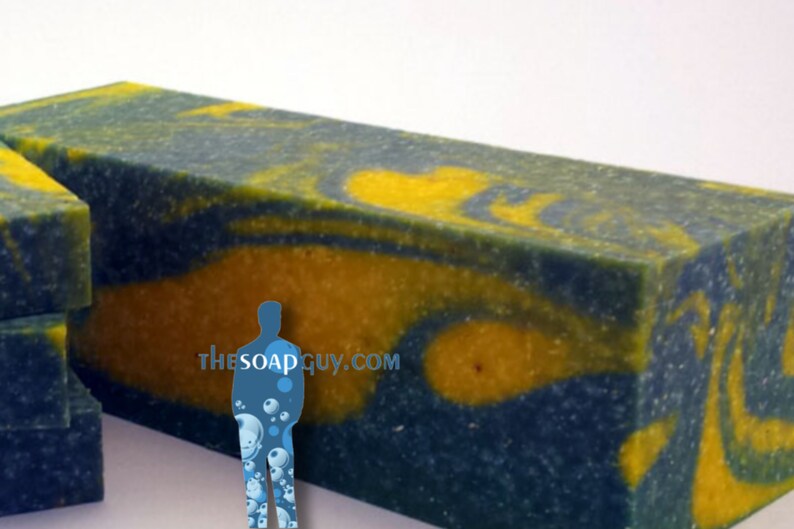 May include: A large bar of handmade soap with a blue and yellow swirl pattern. The soap is textured and has a speckled appearance. The text "thesoapguy.com" is visible on the soap.