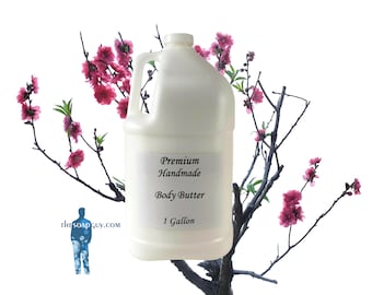 May include: A white plastic gallon jug of premium handmade body butter. The jug has a black label with the text "Premium Handmade Body Butter 1 Gallon". The jug is surrounded by a flowering tree branch with pink blossoms.