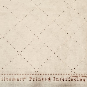 May include: Off-white fabric with a printed diamond grid pattern. The fabric has a dotted grid design and the text "Quiltsmart Printed Interfacing" in brown. Copyright information is also visible.