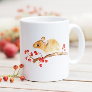 Könnte beinhalten: Weiße Keramiktasse mit einer braunen Maus, die auf einem Zweig mit roten Beeren sitzt. Die Maus schaut nach links.