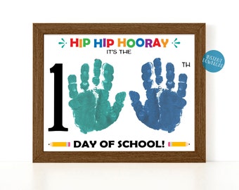 May include: A printable sign with the text "Hip Hip Hooray! It's the 1st Day of School!" with two handprints, one blue and one green.