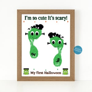 May include: A printable Halloween craft for kids featuring two green monster footprints with googly eyes and stitches. The text reads "I'm so cute it's scary!" and "My first Halloween".