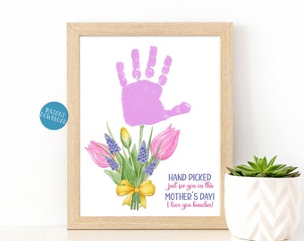 Puede incluir: Una tarjeta para el Día de la Madre imprimible con una huella de mano rosa y un ramo de flores moradas y amarillas. El texto dice "Hand Picked Just for you on this Mother's Day! I love you bunches!"