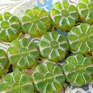 May include: A collection of translucent olive green glass beads shaped like small flowers with eight rounded petals. Each bead features a central hole and a smooth, glossy finish, arranged in a cluster to showcase the uniform color and shape.