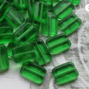 May include: A large pile of green glass beads, each bead is rectangular with a slightly frosted finish.