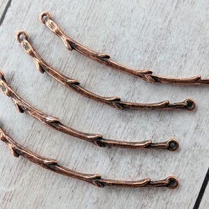 May include: Four curved copper-toned metal connectors shaped like small tree branches. Each piece features a textured, bark-like surface with small protruding nodes and a circular loop at both ends for attachment in jewelry making projects.