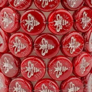 May include: Red glass beads with silver bee designs. The beads are round and have a textured surface.