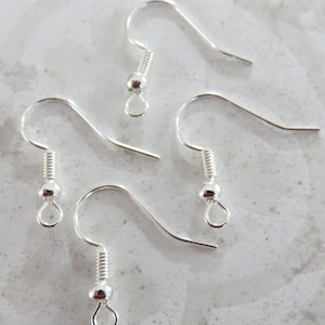 May include: Four silver earring hooks with a small ball at the end of each hook.