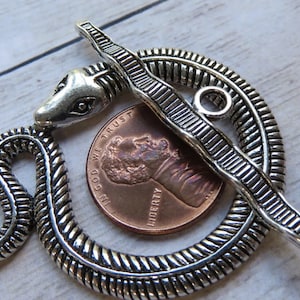 May include: Silver-toned snake-shaped clasp with a textured design. The clasp is approximately the size of a US penny.