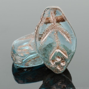 May include: Two light blue glass beads with a silver design. The bead on the right has a more intricate design with a central circle and three smaller circles around it.
