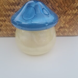 May include: A blue and white ceramic mushroom shaped jar with a shiny, iridescent finish. The jar is filled with a white, glittery substance.