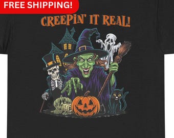 May include: A black t-shirt with a Halloween-themed graphic. The graphic features a witch, a skeleton, a ghost, a black cat, and a pumpkin. The text "Creepin' It Real!" is printed above the graphic.