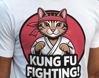 Op de afbeelding: Wit T-shirt met een rode cirkel en een cartoonkat die een wit karatepak en een rood hoofdband draagt. De tekst "KUNG FU FIGHTING!" staat onder de cirkel.