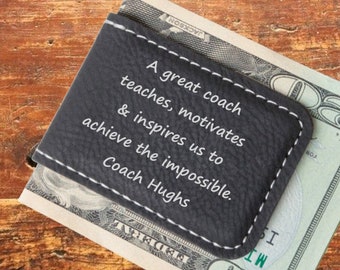 May include: A black leather money clip with white stitching and the inscription "A great coach teaches, motivates & inspires us to achieve the impossible. Coach Hughs".