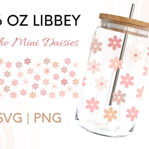 May include: A clear glass tumbler in a Libbey can shape, with a bamboo lid and metal straw. The glass is adorned with a pattern of pink and peach daisy flowers. Text on the left reads "16 OZ LIBBEY" and "Boho Mini Daisies".