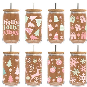 May include: Eight glass tumblers with wooden lids and straws. Each tumbler features a different Christmas-themed design in pink, green, and white. Designs include snowflakes, Christmas trees, presents, candy canes, holly, and bells.