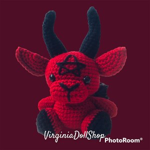 May include: A red and black crocheted plush doll featuring two tall black horns, pointed ears, and a black pentagram stitched onto its forehead. The doll has black plastic eyes, a black stitched nose and mouth, and black feet, with the text VirginiaDollShop.
