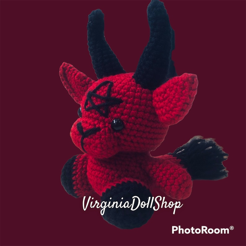 May include: A red and black crocheted plush toy featuring two large black horns, a black pentagram stitched on the forehead, black hooves, and a black tail. The toy has black plastic eyes and the text VirginiaDollShop is visible below it.