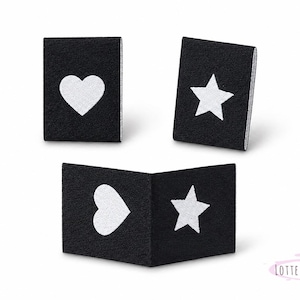 以下が含まれることがあります： 白のハート、星、ハートと星を組み合わせた3つの黒い布ブロック。これらのブロックは、ベビーおもちゃや教育教材に適した、視覚的に魅力的な構成で配置されています。