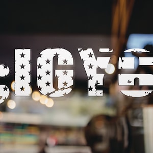 May include: A white sign with the text ":ICY" in a distressed font. The letters are filled with a pattern of white stars on a blue background, resembling the American flag.