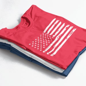 Peut inclure: Un lot de trois t-shirts, le haut est rouge avec un motif de drapeau am&eacute;ricain blanc d&eacute;lav&eacute;.