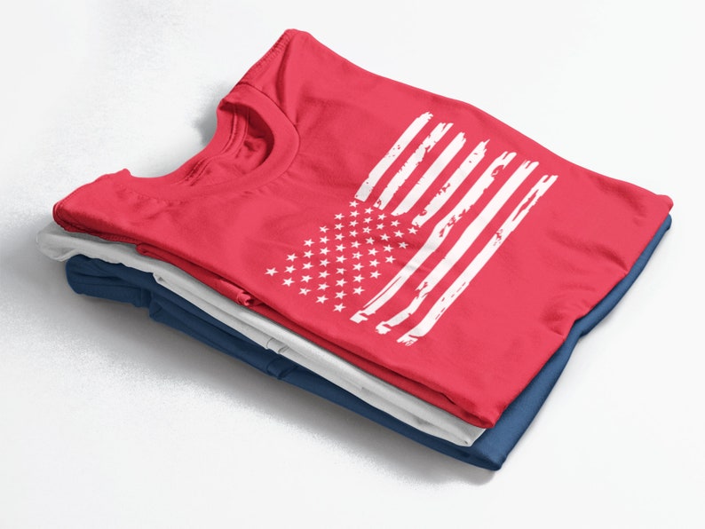 Peut inclure: Un lot de trois t-shirts, le haut est rouge avec un motif de drapeau am&eacute;ricain blanc d&eacute;lav&eacute;.