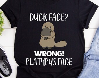 May include: Black t-shirt with a cartoon platypus and the text "Duck Face? Wrong! Platypus Face."