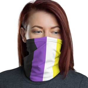 May include: A face mask with a striped pattern in black, purple, white and yellow. The mask is being worn by a person with red hair.