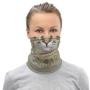 Puede incluir: Una mujer usando una m&aacute;scara facial gris con una cara de gato impresa en ella. La m&aacute;scara est&aacute; hecha de una tela suave y transpirable y est&aacute; dise&ntilde;ada para ser c&oacute;moda de llevar.