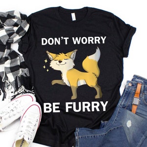 Puede incluir: Camiseta negra con un gr&aacute;fico blanco de un zorro de dibujos animados y el texto "Don't Worry Be Furry".