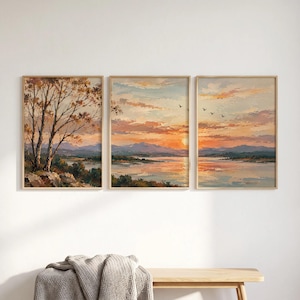 Può includere: Un trittico di dipinti paesaggistici che raffigura un tramonto su un lago con montagne in lontananza. Il pannello di sinistra mostra un albero su una riva rocciosa, mentre i pannelli centrale e destro ritraggono un cielo arancione vibrante.