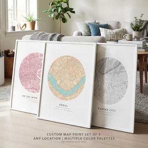 May include: Three framed custom map prints in white frames. The maps are circular, with the cities of Ho Chi Minh, Seoul, and Kansas City displayed in pink, tan, and gray color palettes. The text at the bottom reads "CUSTOM MAP PRINT SET OF 3 ANY LOCATION | MULTIPLE COLOR PALETTES ARTYFRANCISCO SHOP."