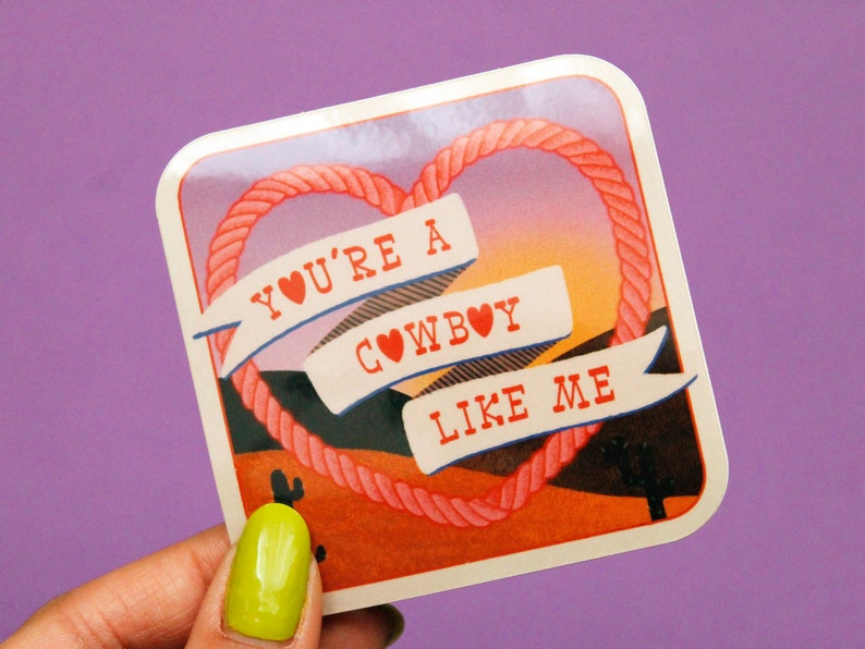 May include: A pink heart-shaped rope design with the text "You're a cowboy like me" on a sticker with a sunset background.