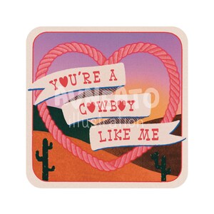 May include: A pink and red rope heart with a sunset background. The heart has a banner that says "You're a Cowboy Like Me" with a small heart in the text.