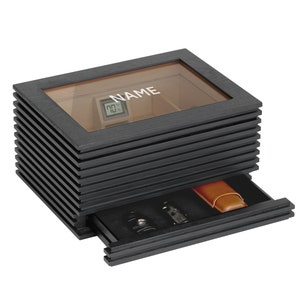 May include: A black wooden humidor with a glass top and a drawer. The humidor has a digital hygrometer and the text "NAME" on the top.