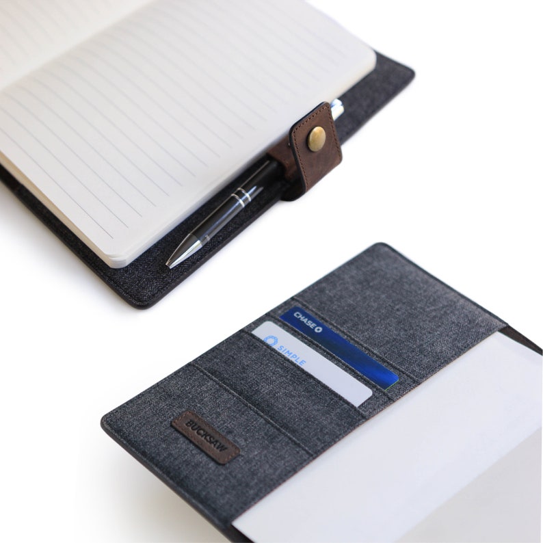 May include: A gray fabric notebook with a brown leather flap and a pen holder. The notebook has a card slot and the text "BUCKSAW" on the front. The notebook is open and a white page is visible.