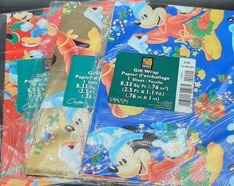 Puede incluir: Varias hojas de papel de regalo con temática navideña con Mickey Mouse con atuendo festivo. El papel de regalo tiene una variedad de colores, incluyendo rojo, dorado y azul, con imágenes de Mickey, bastones de caramelo y otras decoraciones navideñas.