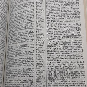 May include: An open book with text from the Bible, featuring the word "Ezekiel" at the top. The pages are yellowed, and the book is open to a chapter with multiple verses.