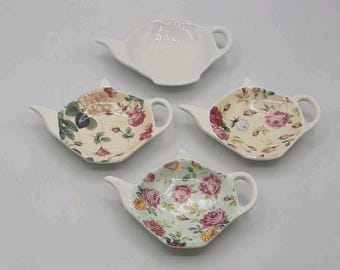 Juego de cuatro posavasos y soportes para bolsitas de té decorativos con forma de tetera.