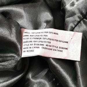 May include: A close-up of a garment's interior, displaying a label with fabric composition details. The label states "SHELL: 50% POLYESTER 50% WOOL" and "LINING: 100% POLYESTER." The garment is made in China.