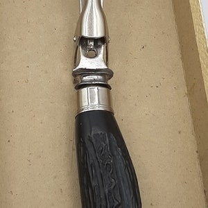 Puede incluir: Un tenedor para trinchar vintage con cabeza de acero inoxidable y mango oscuro y texturizado. El tenedor tiene dos p&uacute;as y una virola decorativa. El mango parece ser de madera tallada o similar.